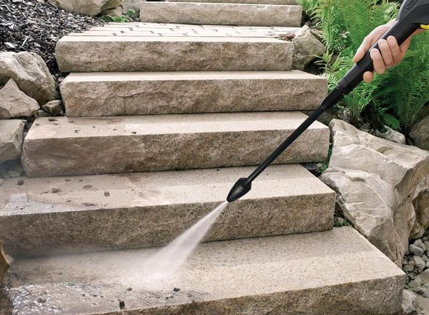 A pressure washer being used on concrete garden steps.