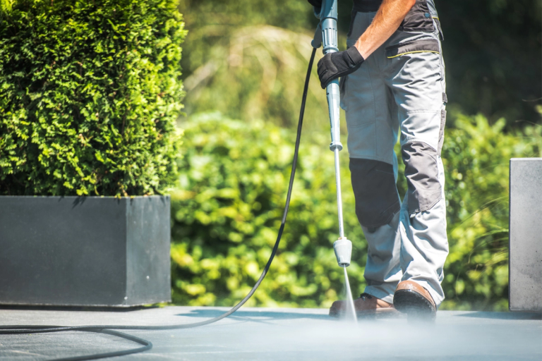 Person wearing safety shoes using a pressure washer to clean the ground