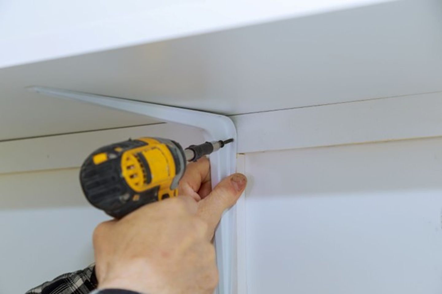 A person drilling a hole in a shelf