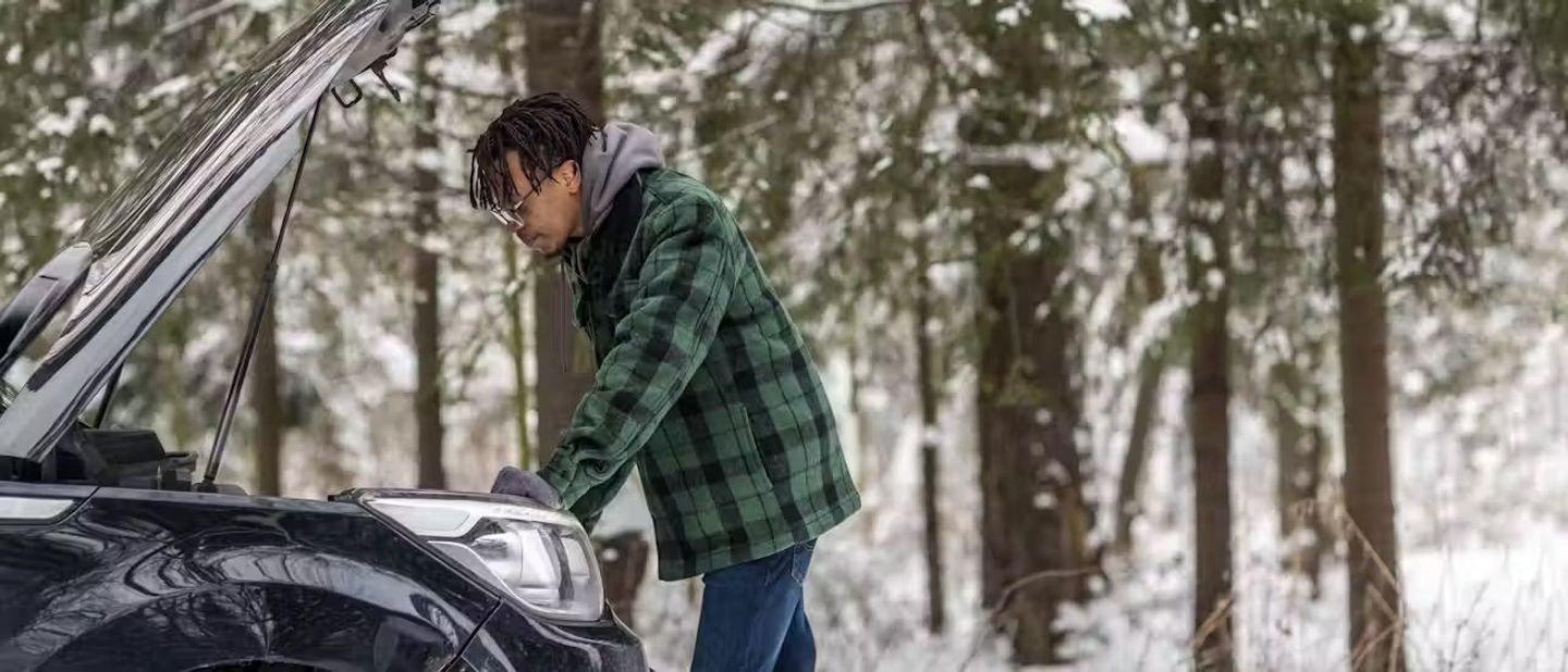 man checking cars engine during the winter