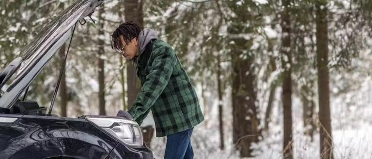 man checking cars engine during the winter