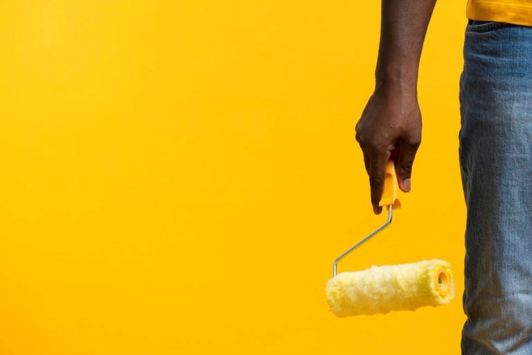 man with a paint roller on the yellow background