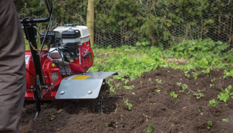 Someone using a rotavator on soil.