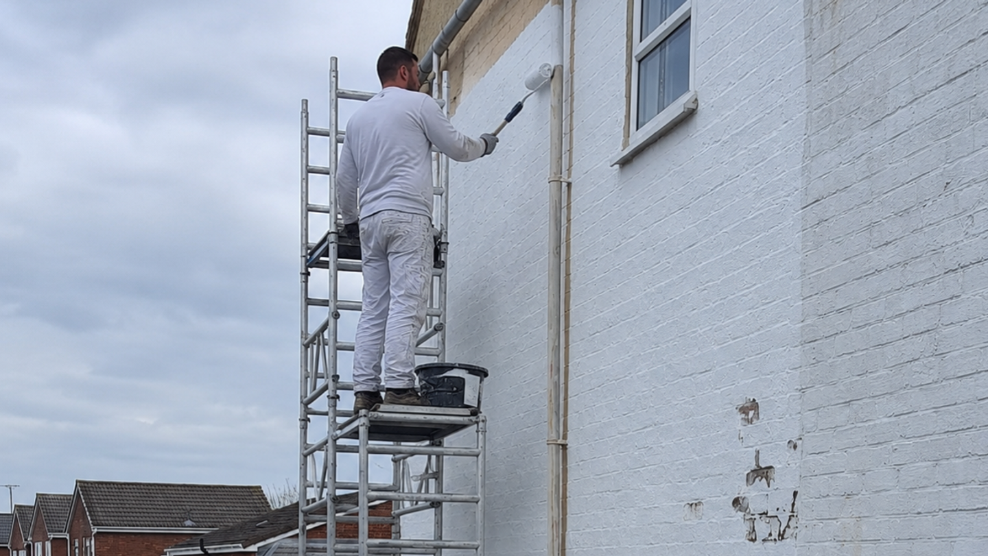 man painting external house wall