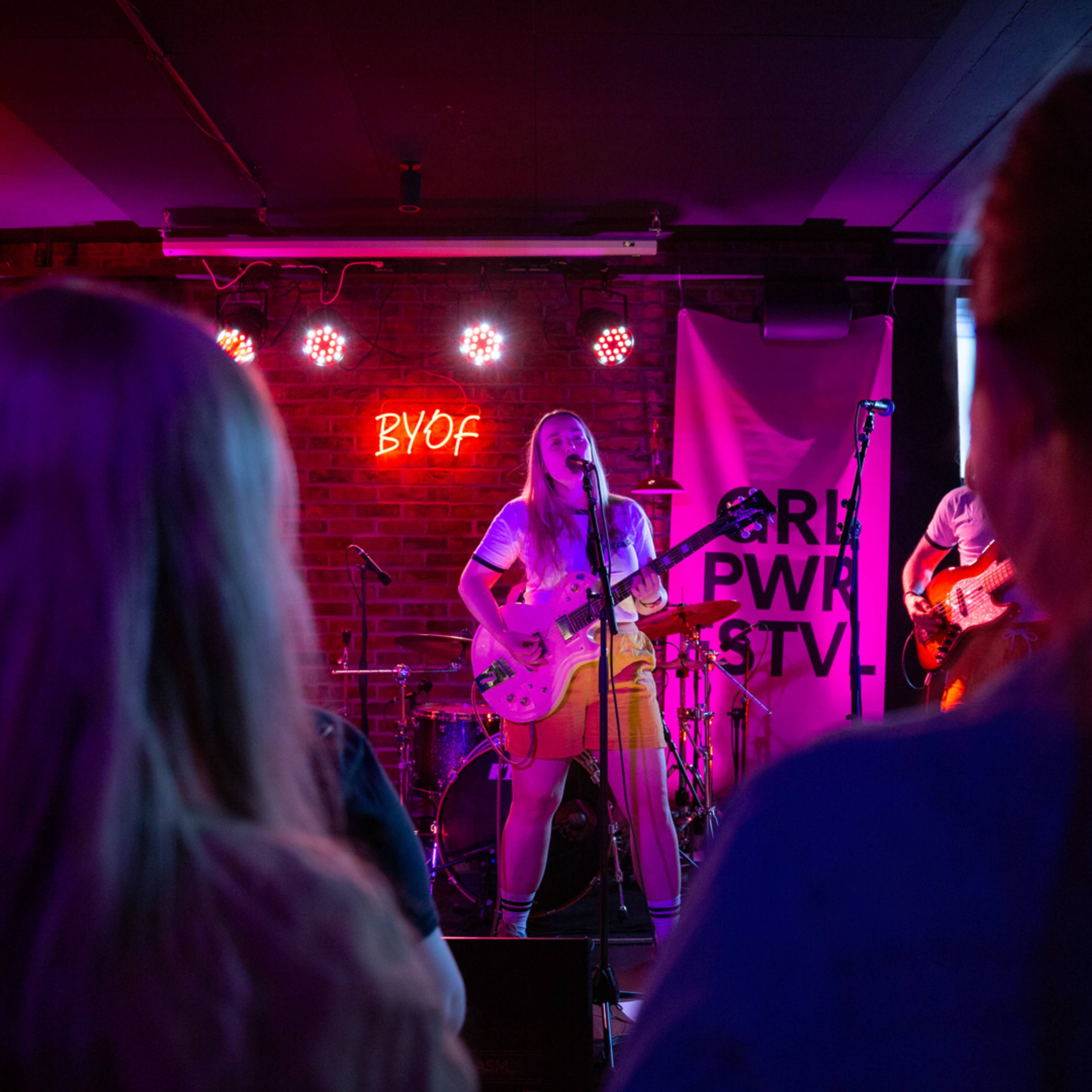 vokalist med gitar på en scene på baren tæps