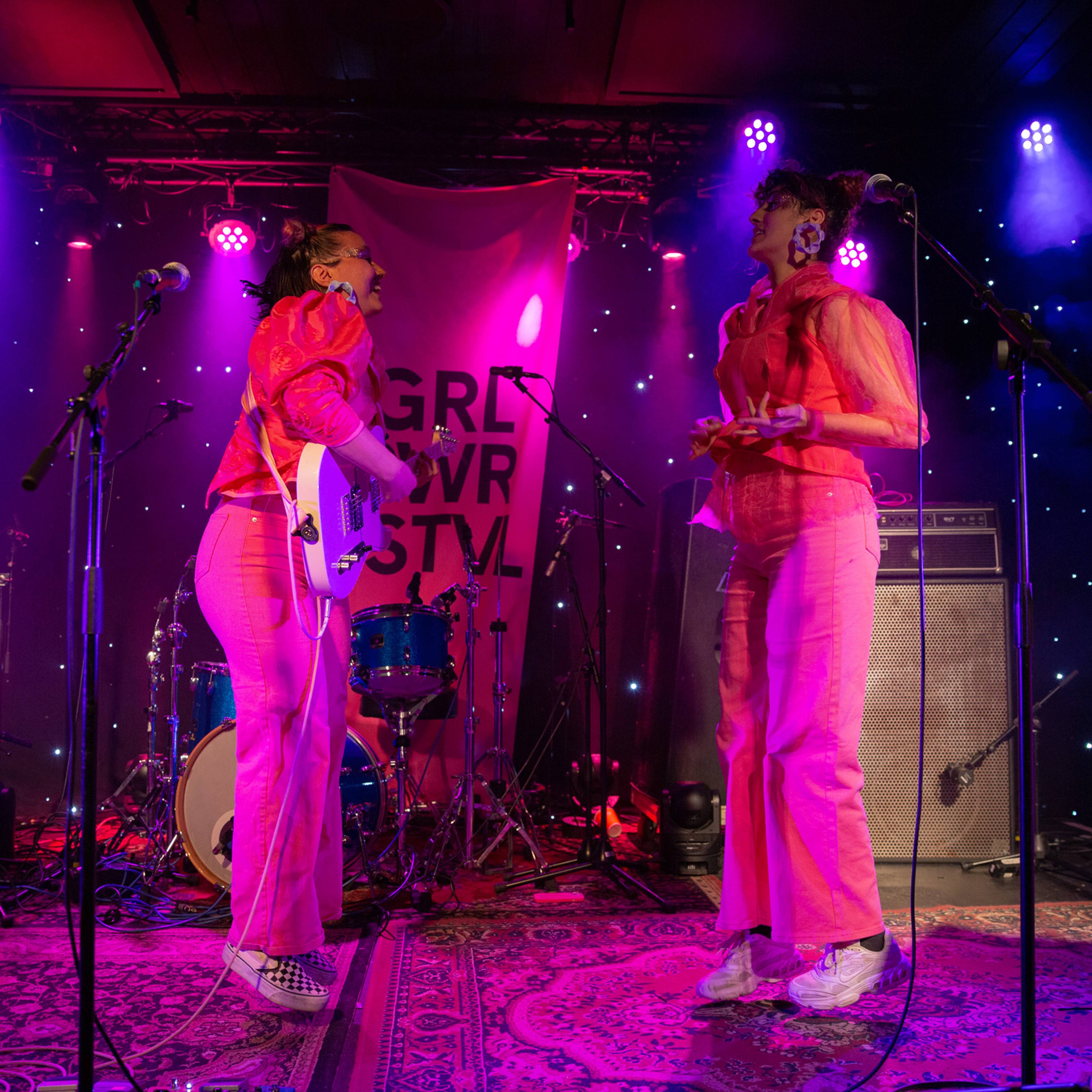 to kvinner på scenen som hopper og er kledd i rosa 