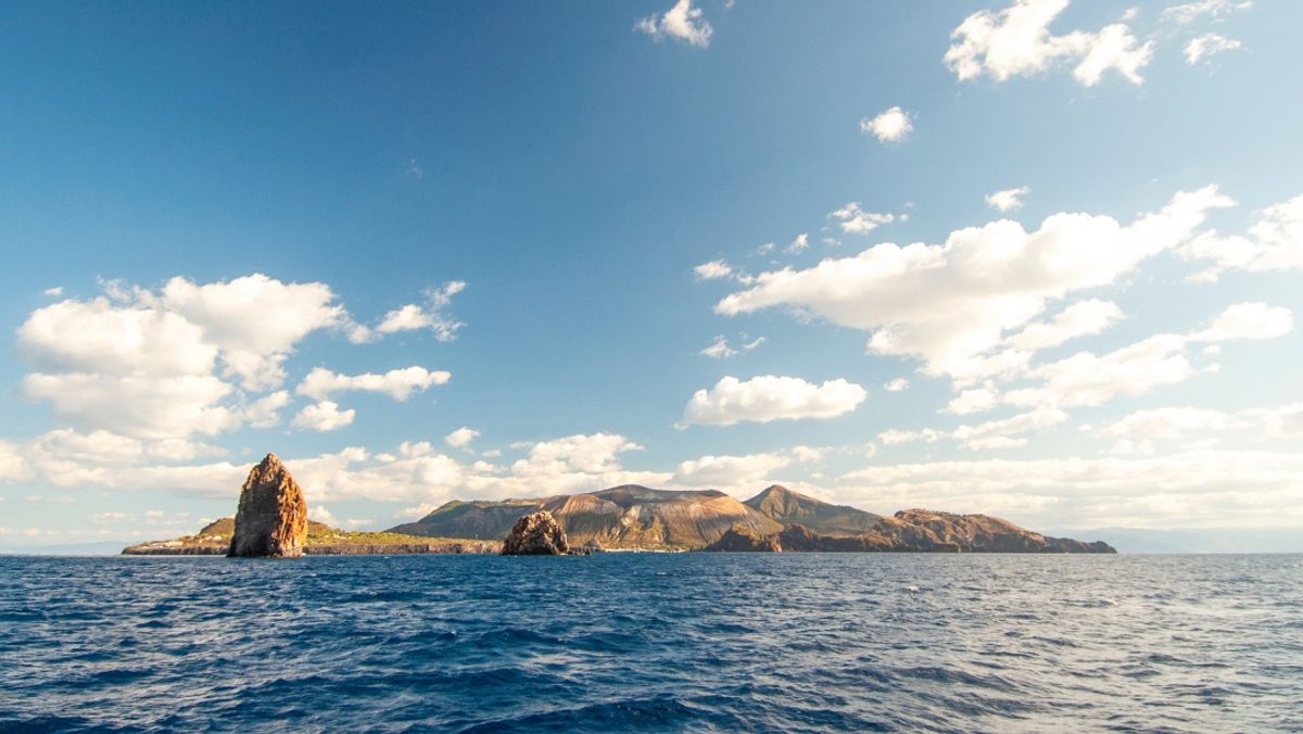 The stromboli vulcano erupting on the "Sciara del Fuoco"(path of lava) day panoramic shot, blue sky background, eolians islands, sicily, italy.