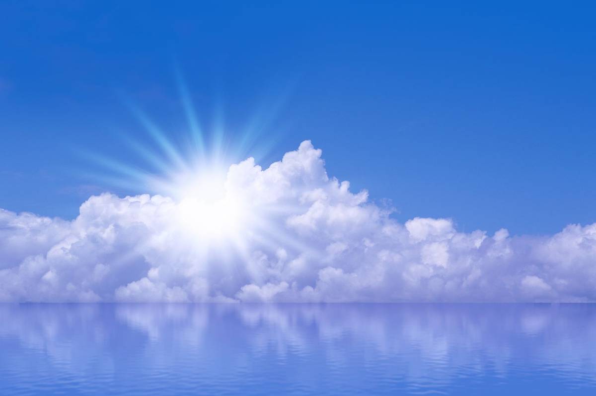 Sonne bricht strahlend über einer Wolkenbank hervor, darunter ruhiges Wasser