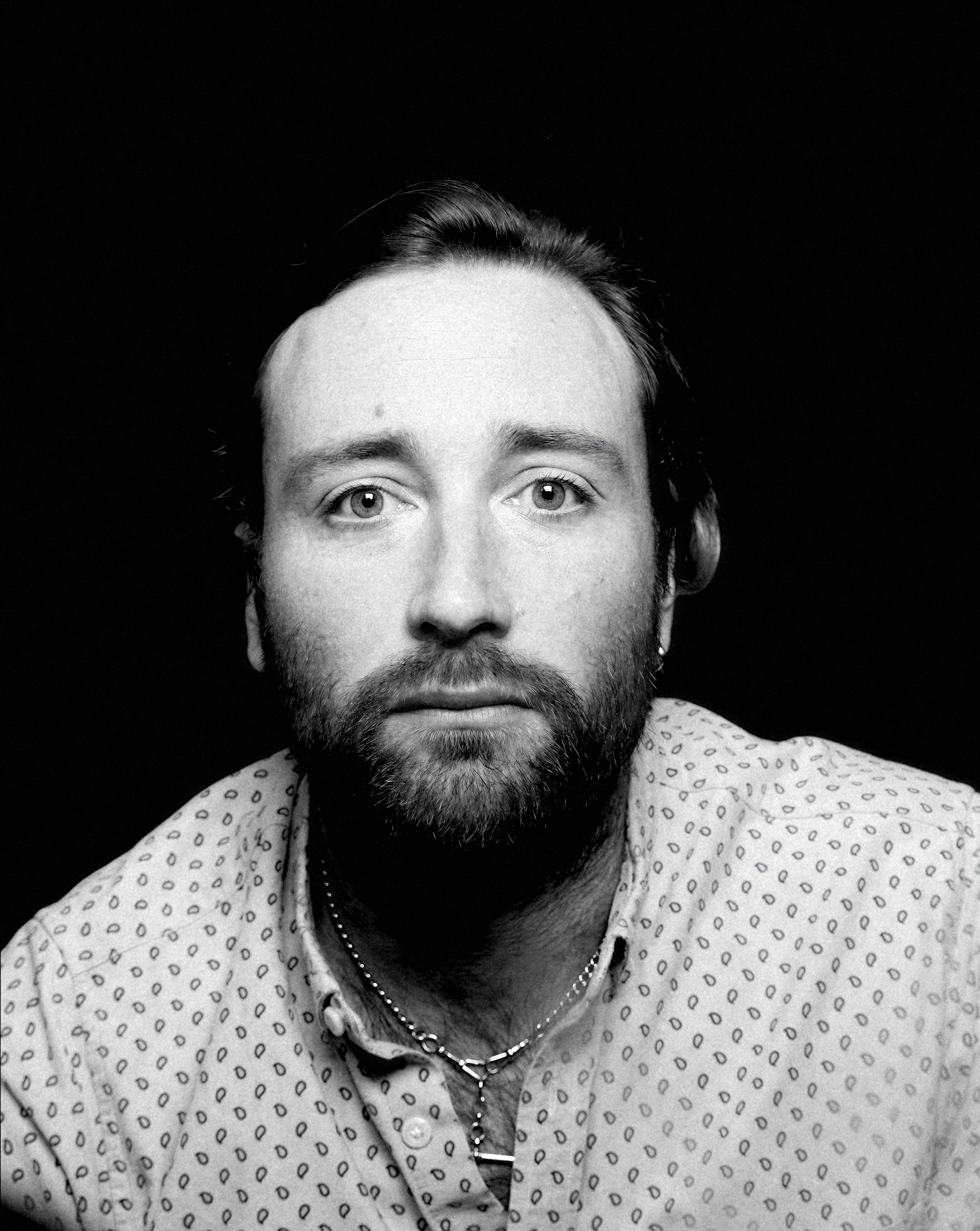 a man with short brown hair wearing a black tee-shirt