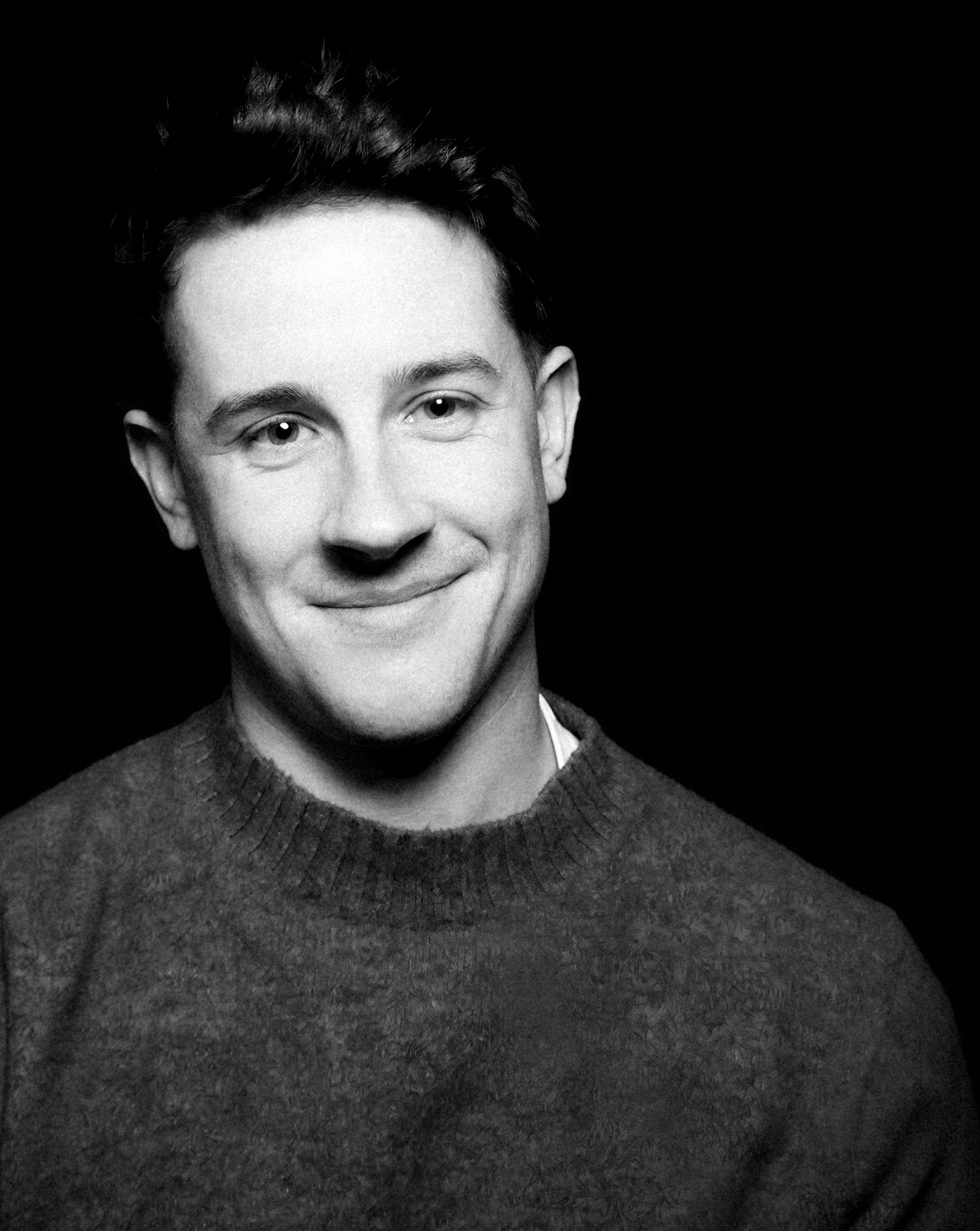 a man with short brown hair wearing a black tee-shirt