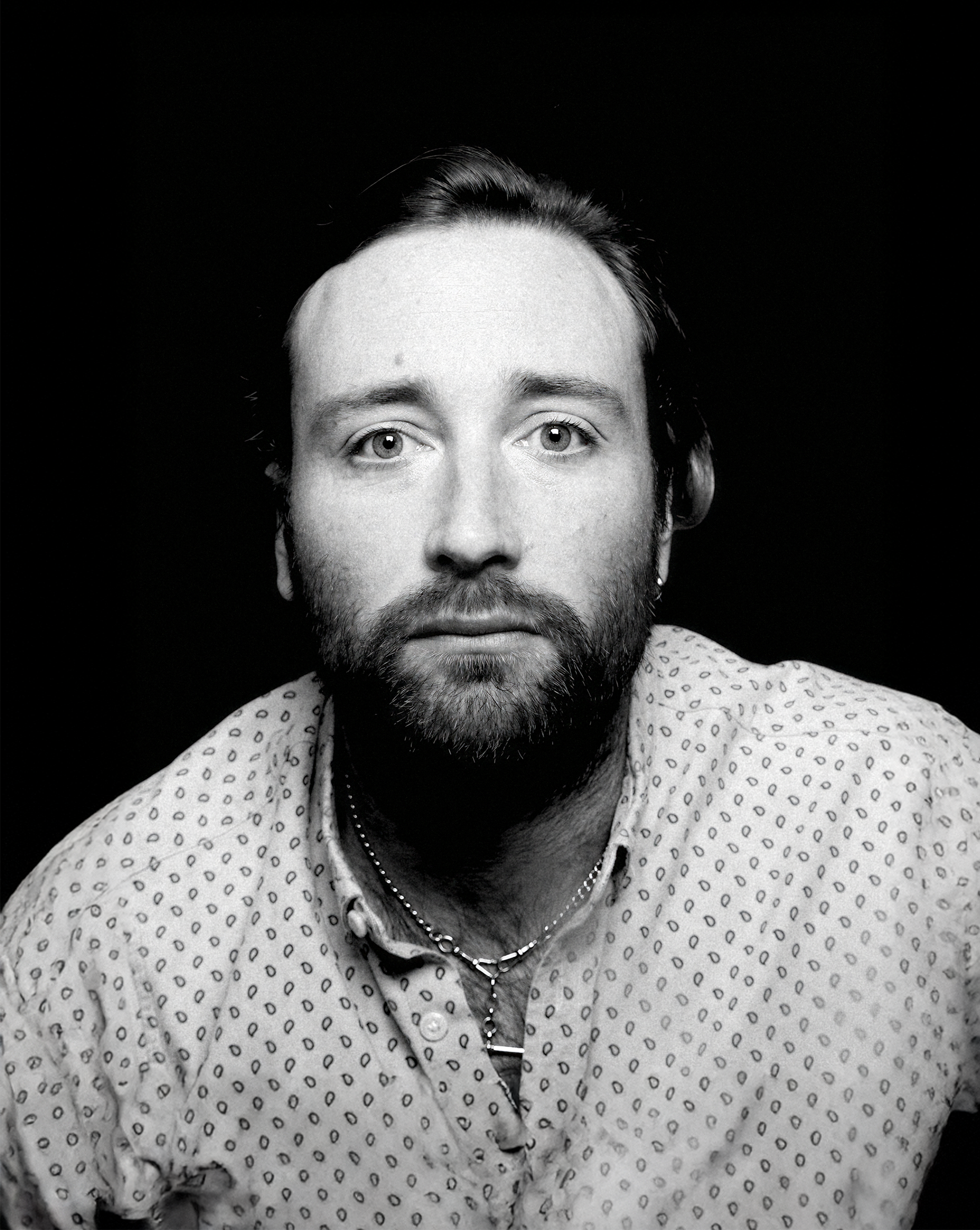 a man with short brown hair wearing a black tee-shirt