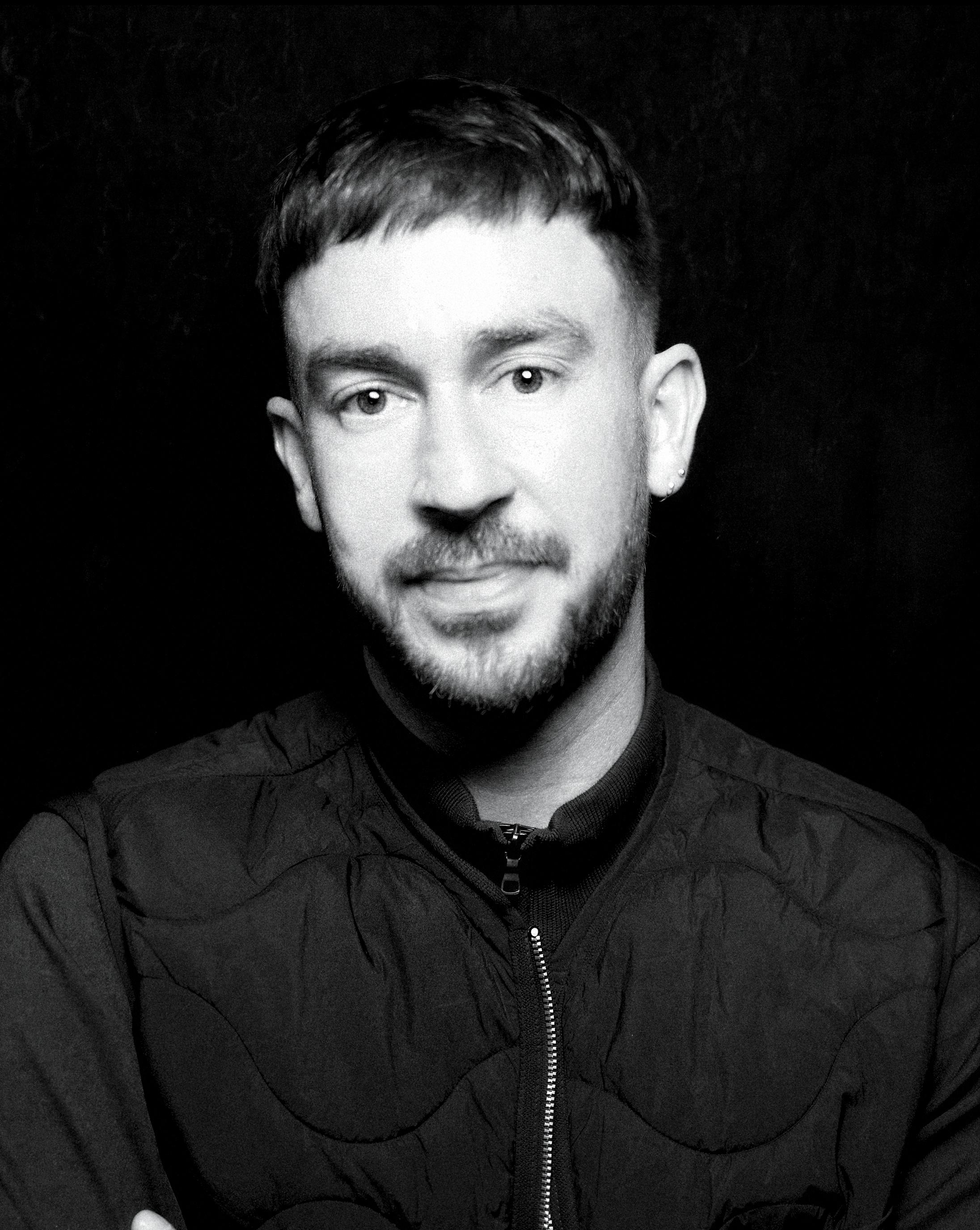 a man with short brown hair wearing a black tee-shirt