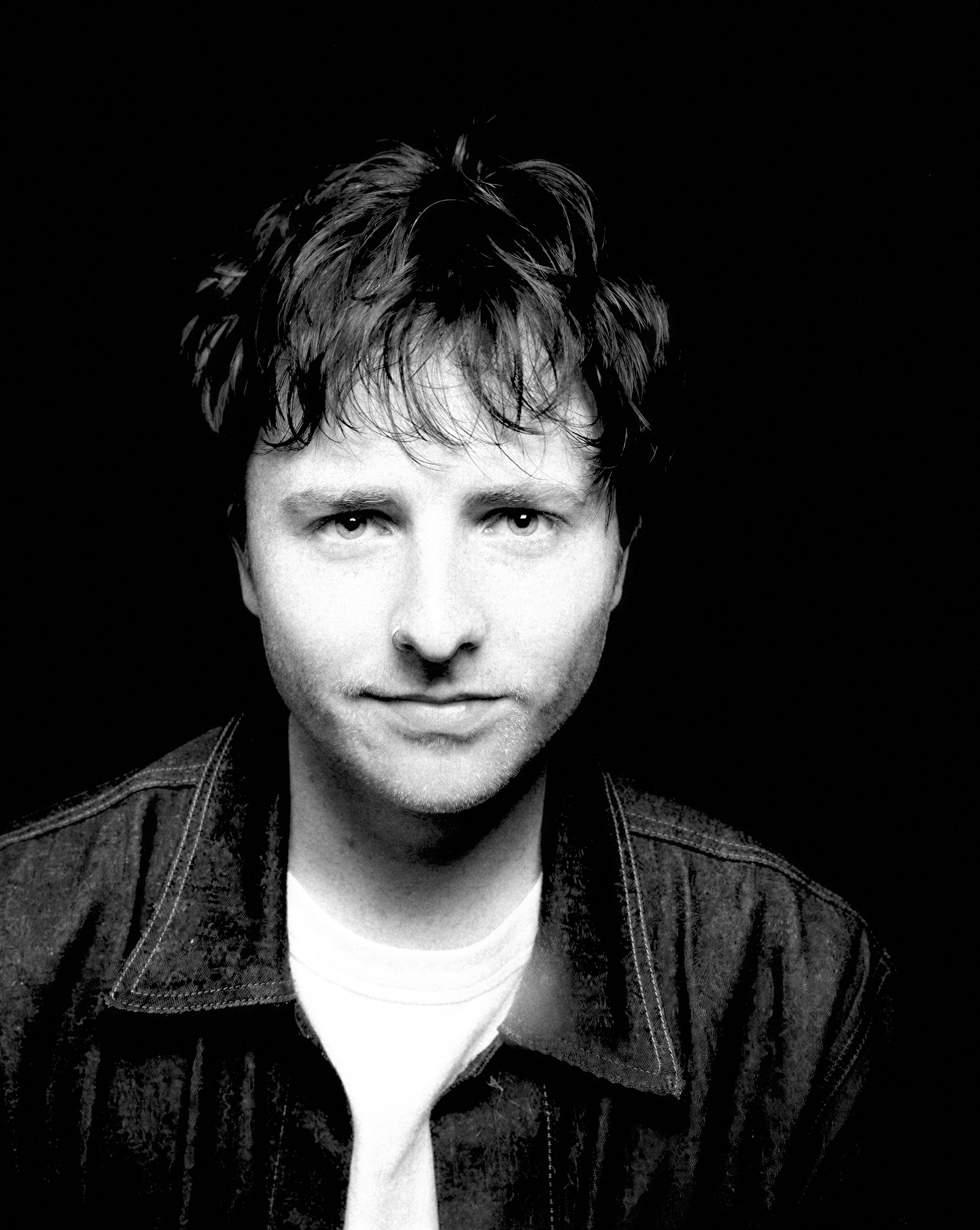 a man with black hair wearing a black coat