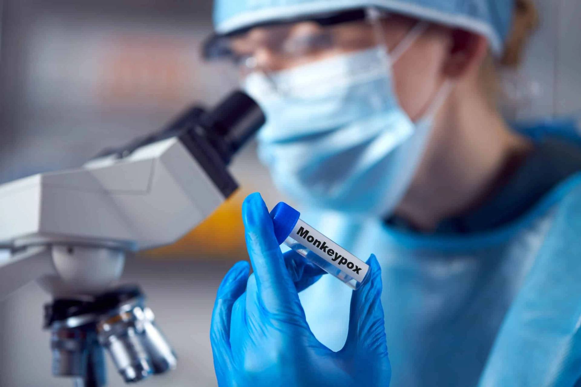 Personne masquée travaillant au microscope dans un laboratoire.