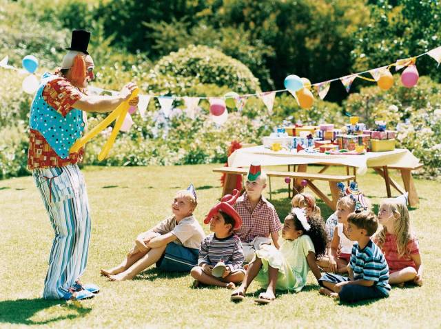 Clown animant une fête d’enfants dans un jardin.