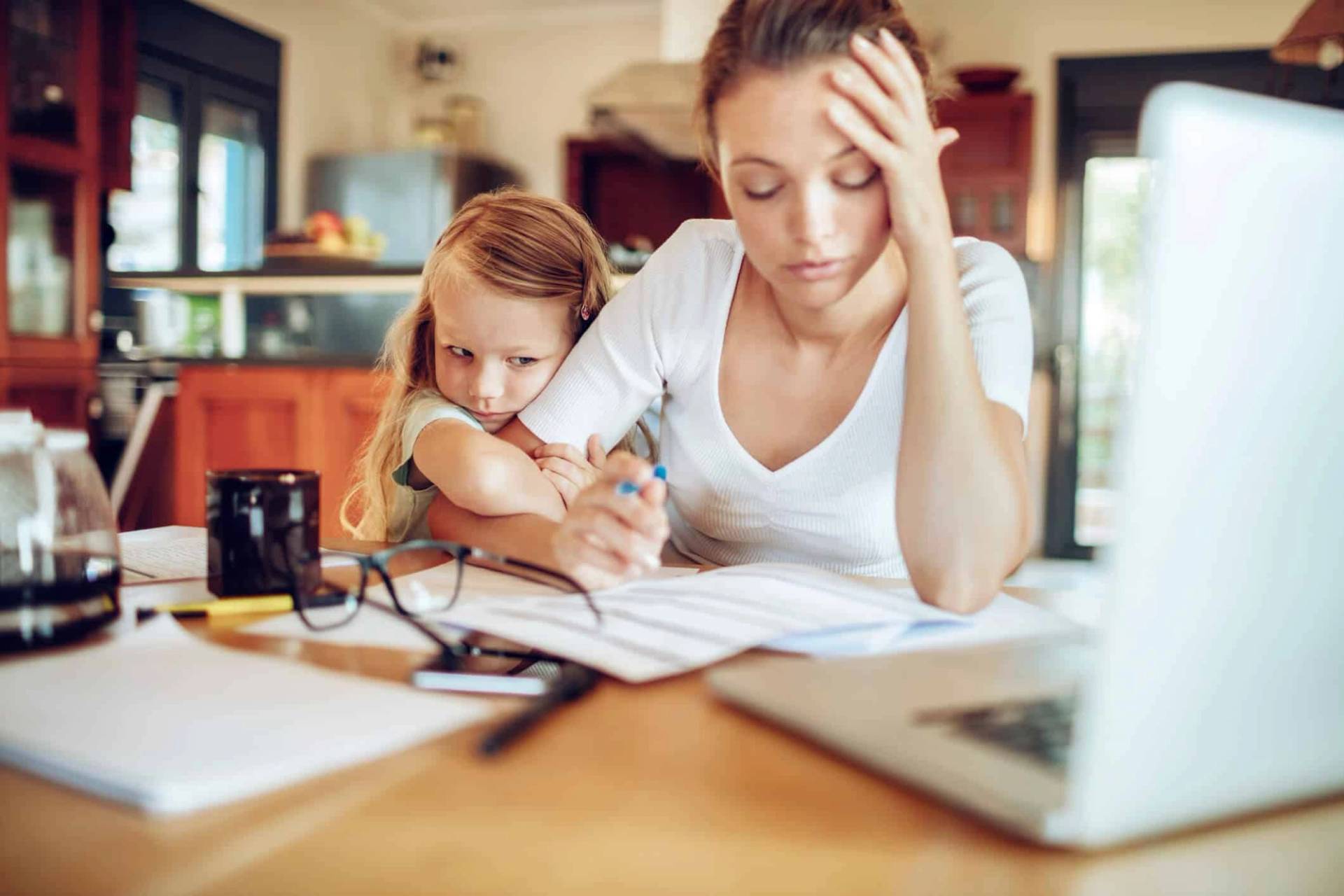 Adulte travaillant sur un ordinateur avec un enfant à ses côtés.