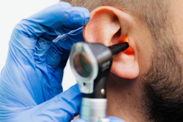 Examen d’une oreille avec un otoscope, en gros plan.