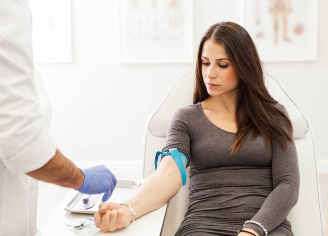 Professionnel de santé effectuant une prise de sang pour mesurer le taux de glycémie d'une patiente