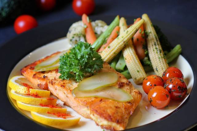 Un plat de saumon joliment dressé avec des légumes frais et des tranches de citron, parfait pour un repas gourmet