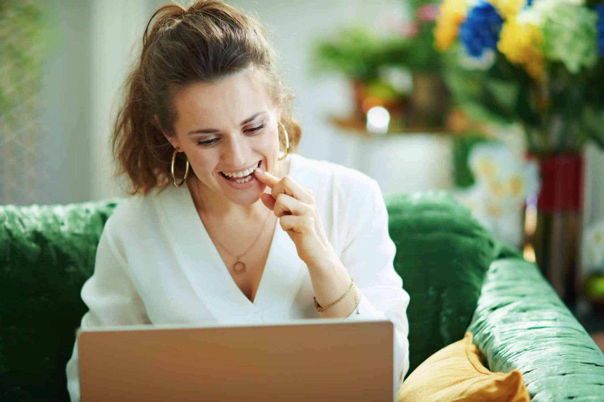 Femme devant un ordinateur portable, la main près de la bouche.