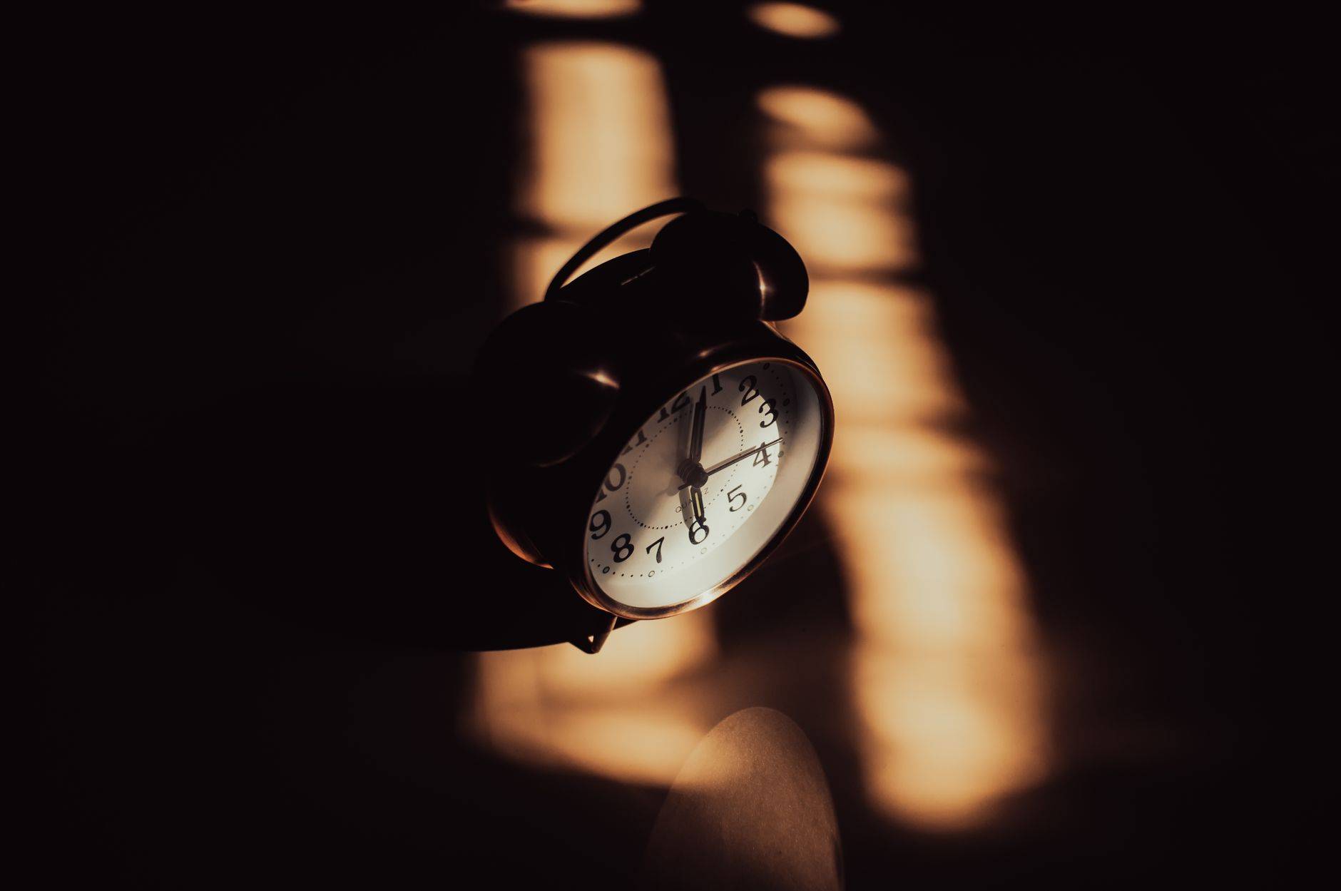 Un réveil analogique rétro dans des ombres d'ambiance et un éclairage chaud