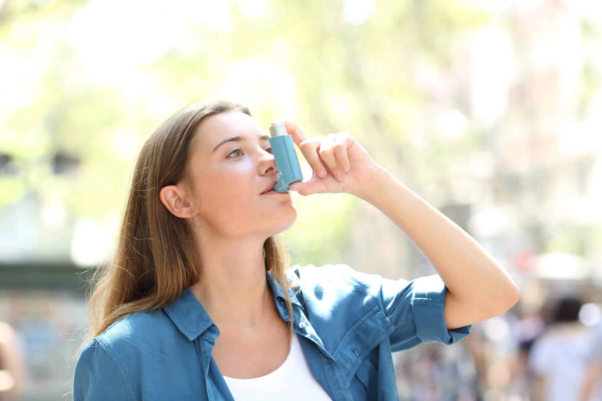 Femme utilisant un inhalateur à l’extérieur.