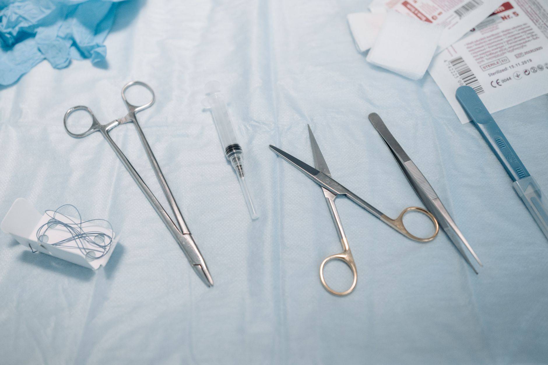Instruments médicaux, seringue et compresses disposés sur un champ bleu.