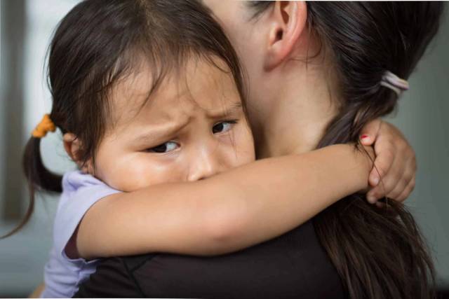 Enfant serrant un adulte dans ses bras.