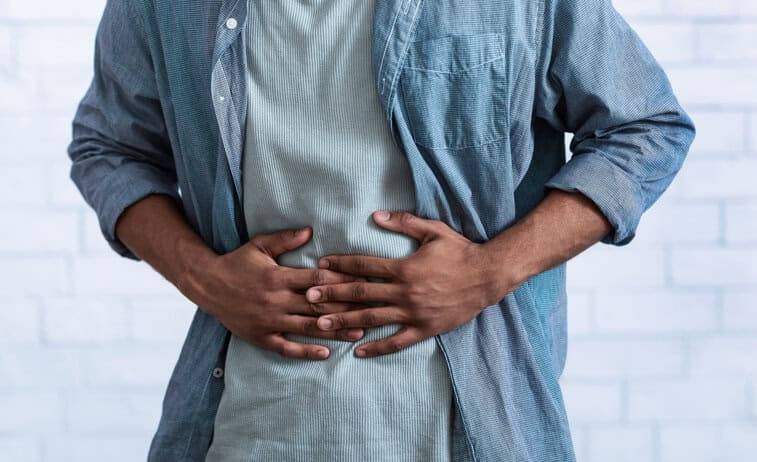 Homme debout avec les mains sur l’abdomen.