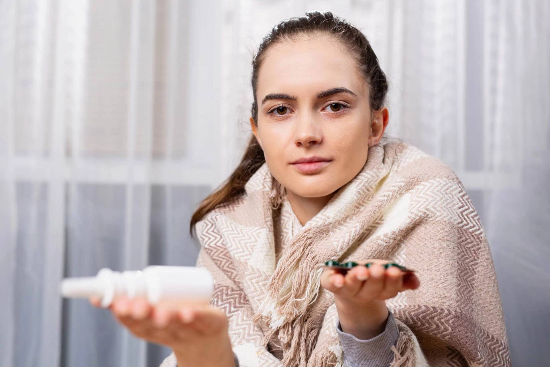 Femme enveloppée dans une couverture tenant des médicaments.