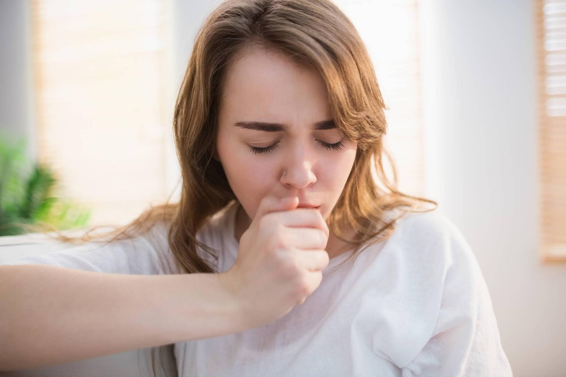 Femme toussant avec la main devant la bouche.