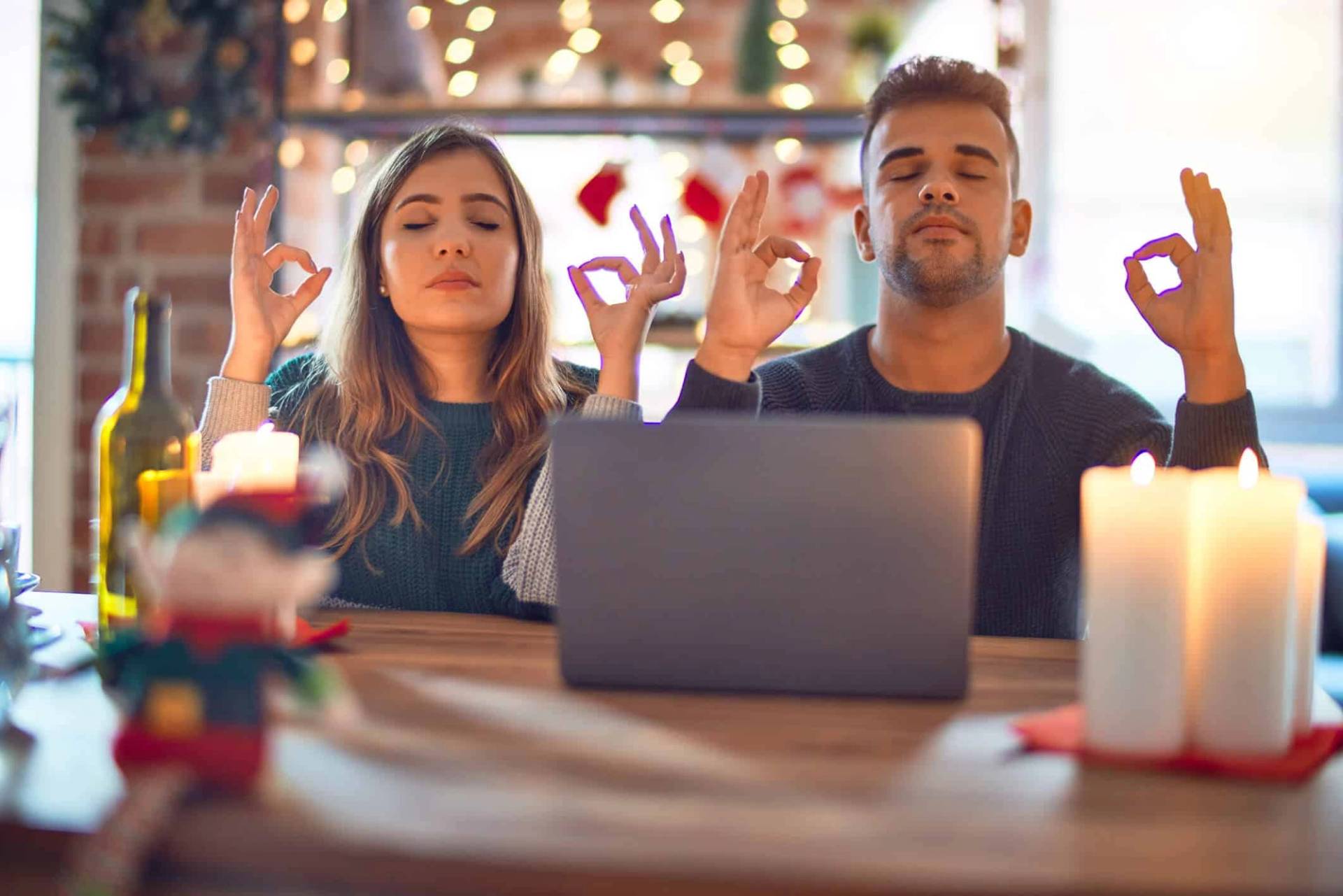 Deux personnes font un geste de relaxation devant un ordinateur et des décorations de Noël.