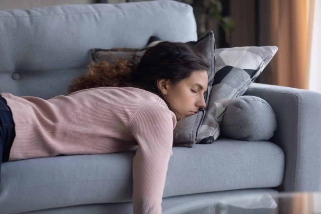 Femme épuisée qui dort sur son canapé