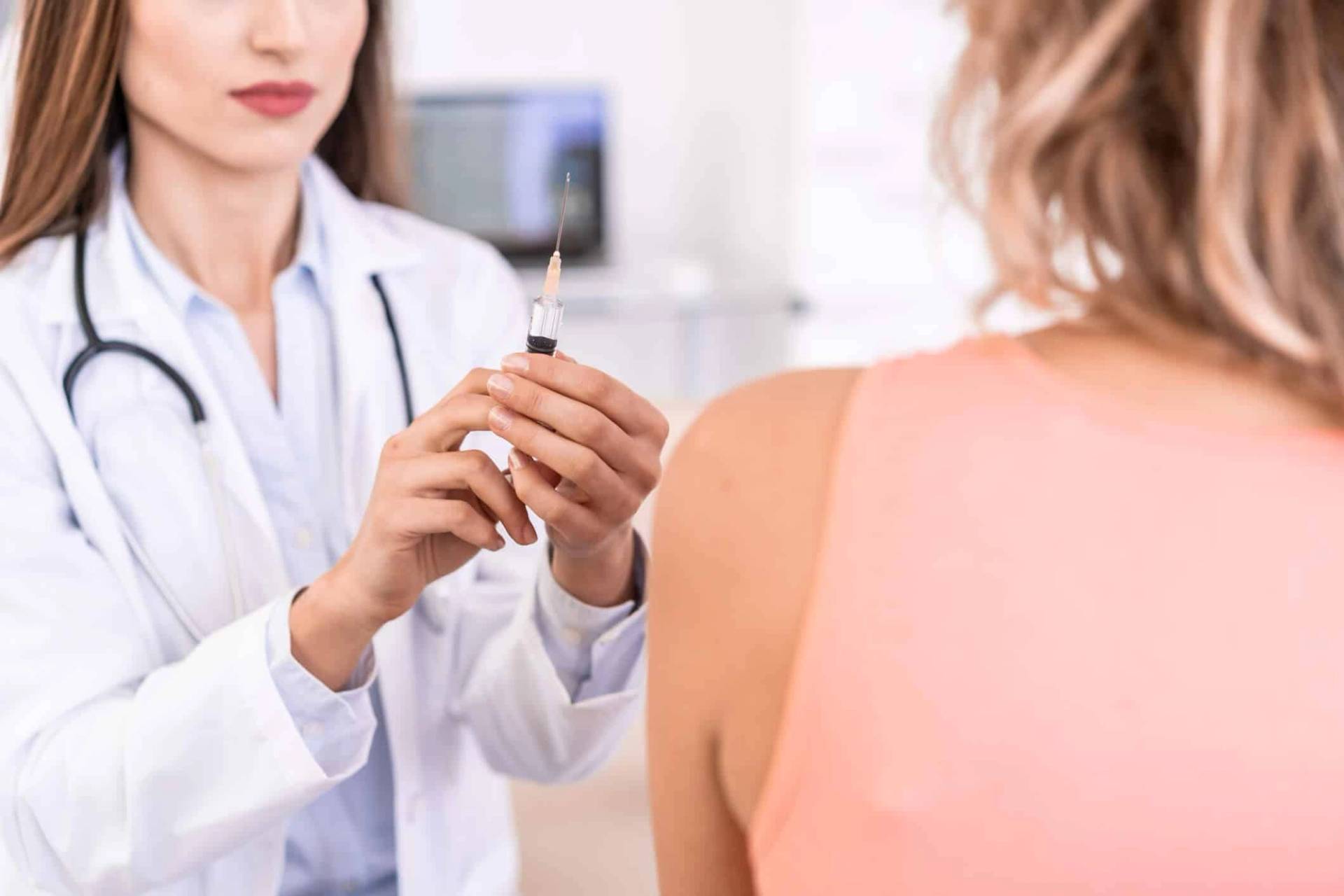Médecin tenant une seringue et le vaccin contre la grippe prête à vacciner sa patiente
