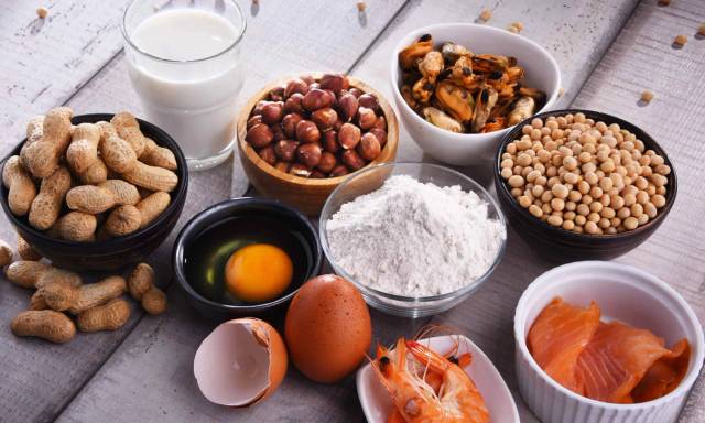 Œufs, poisson, lait, fruits à coque et autres aliments disposés sur une table.