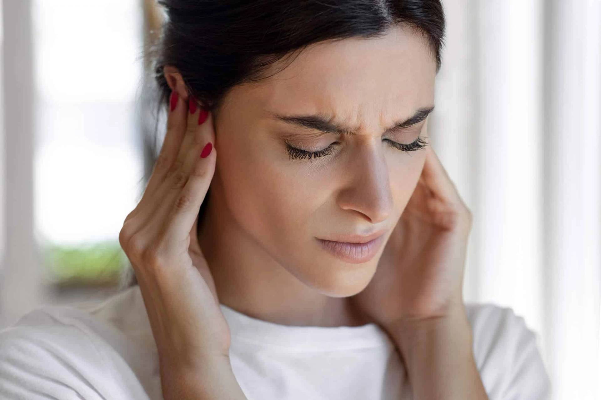 Femme se tenant l'oreille, illustrant les symptômes du bourdonnement d'oreille et des acouphènes