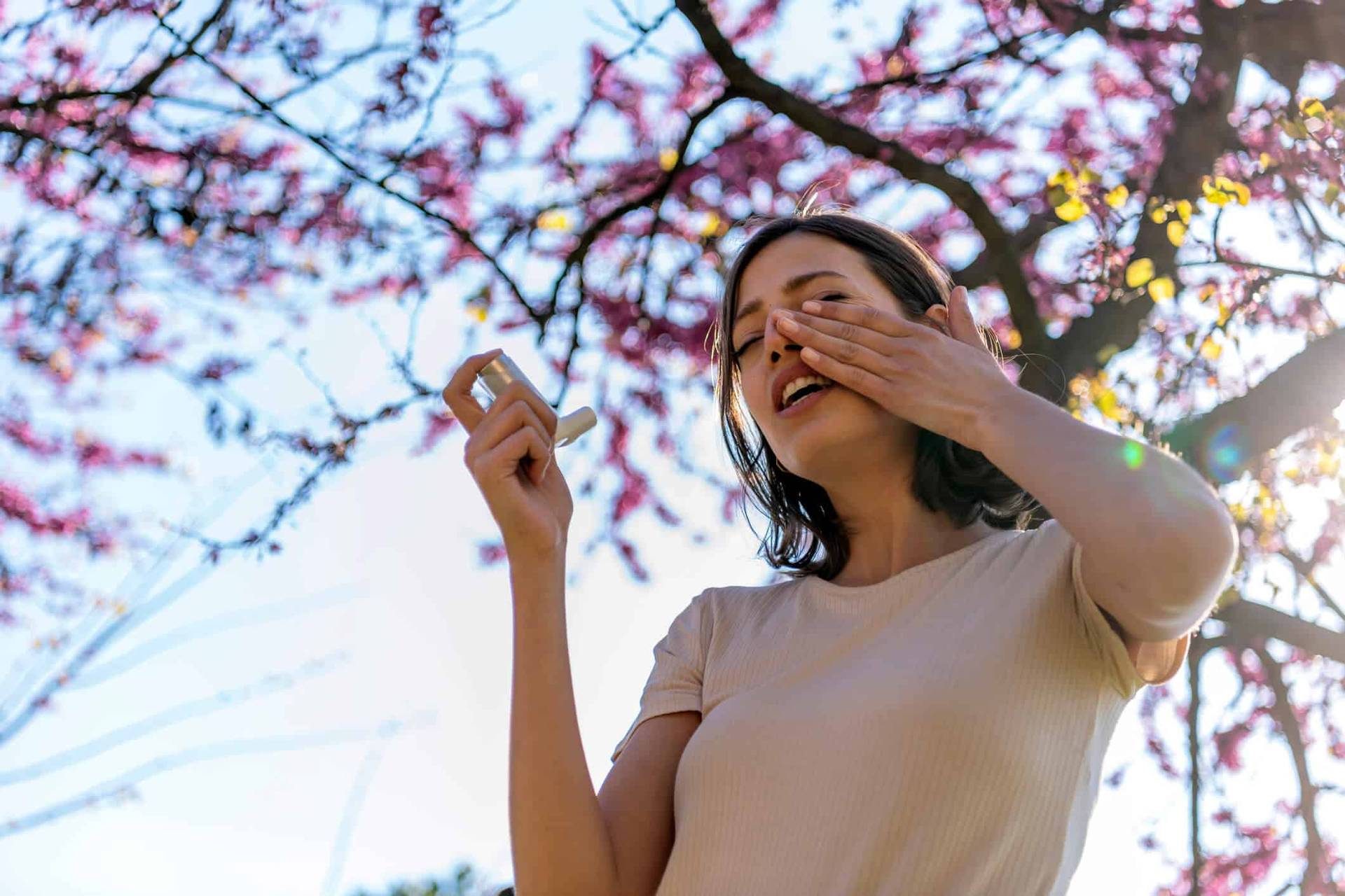 Femme avec un mouchoir près d’un arbre en fleurs.