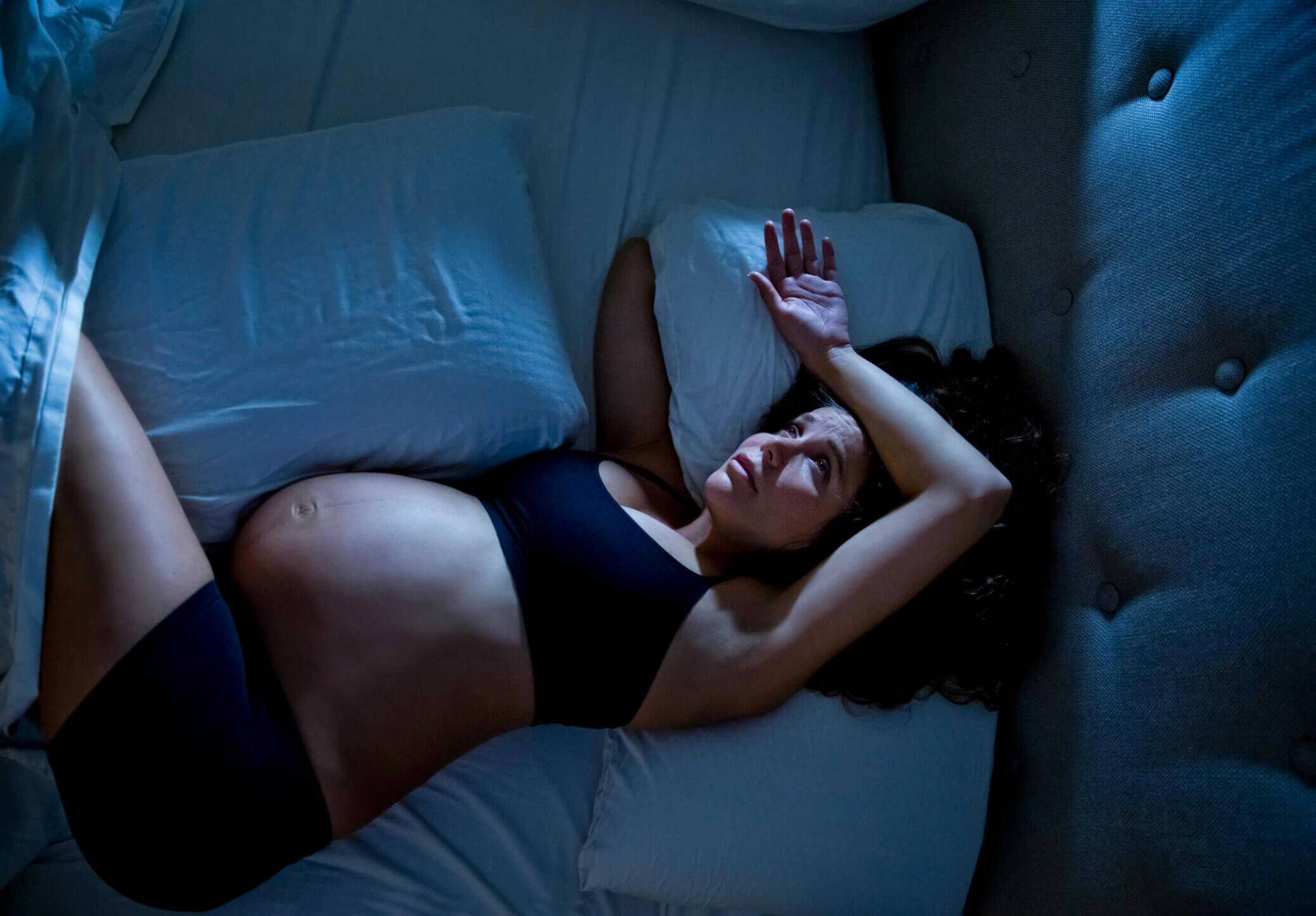 Personne éveillée dans un lit sombre, regardant son téléphone.