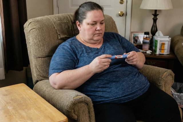 Femme obèse dans son fauteuil avec un stylo à injection contenant du sémaglutide