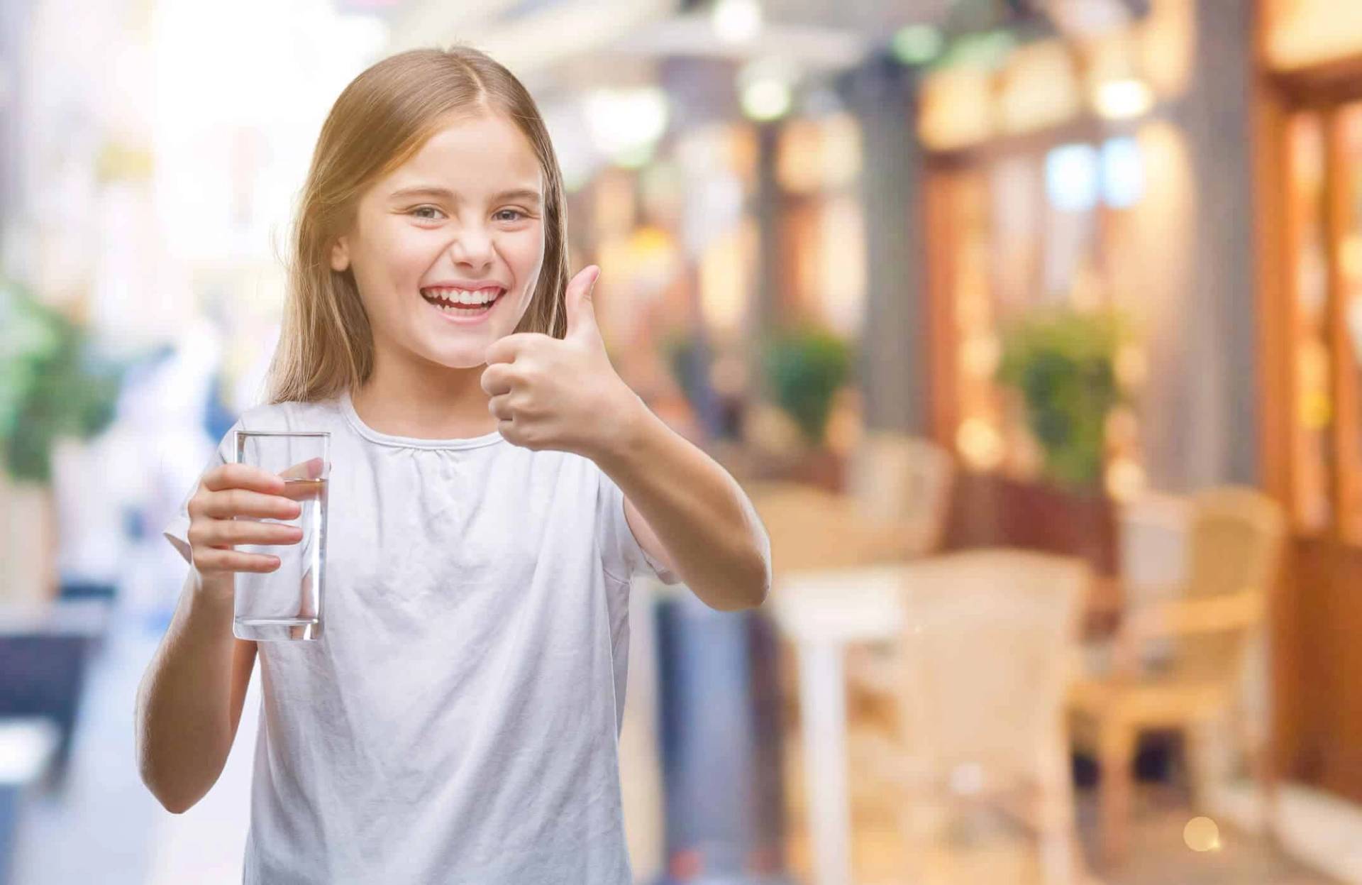 Enfant tenant un verre d’eau et levant le pouce.