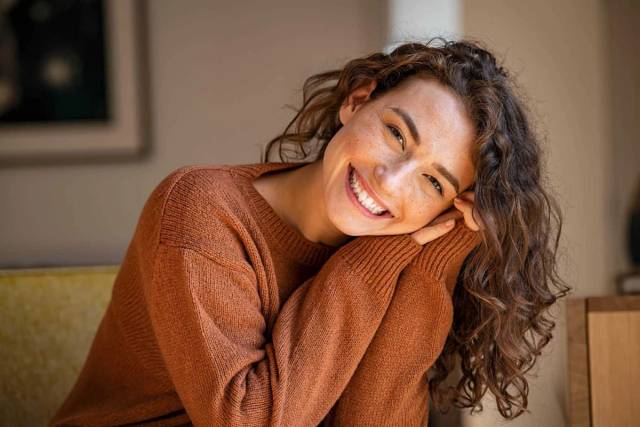 Portrait d’une femme souriante dans un pull.