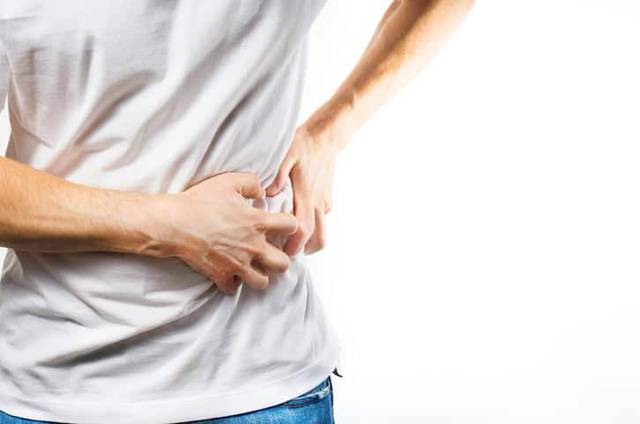 Personne tenant le côté de son abdomen.