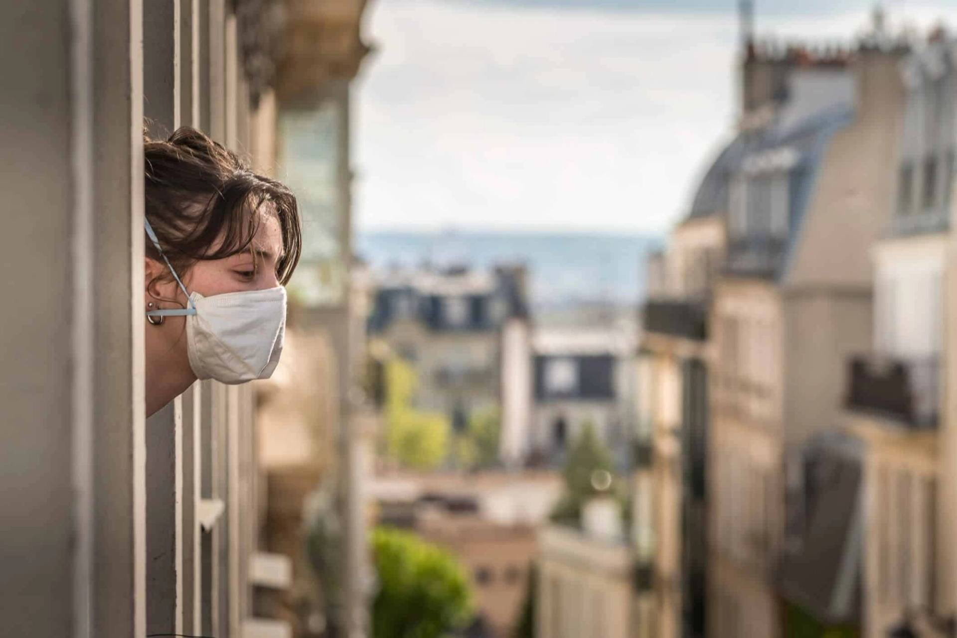 Personne masquée regardant dehors depuis une fenêtre.