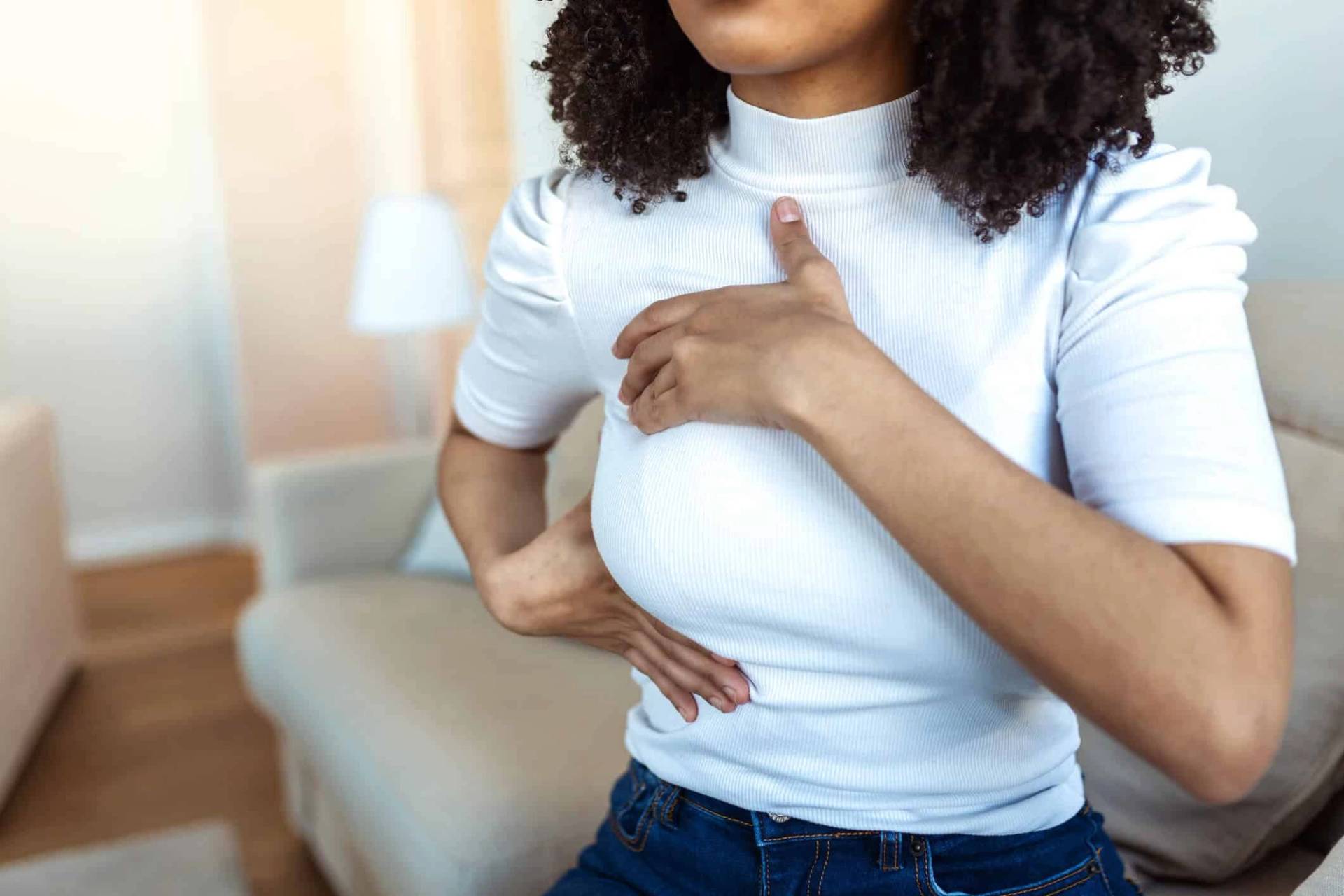 Femme touchant sa poitrine à travers son vêtement.