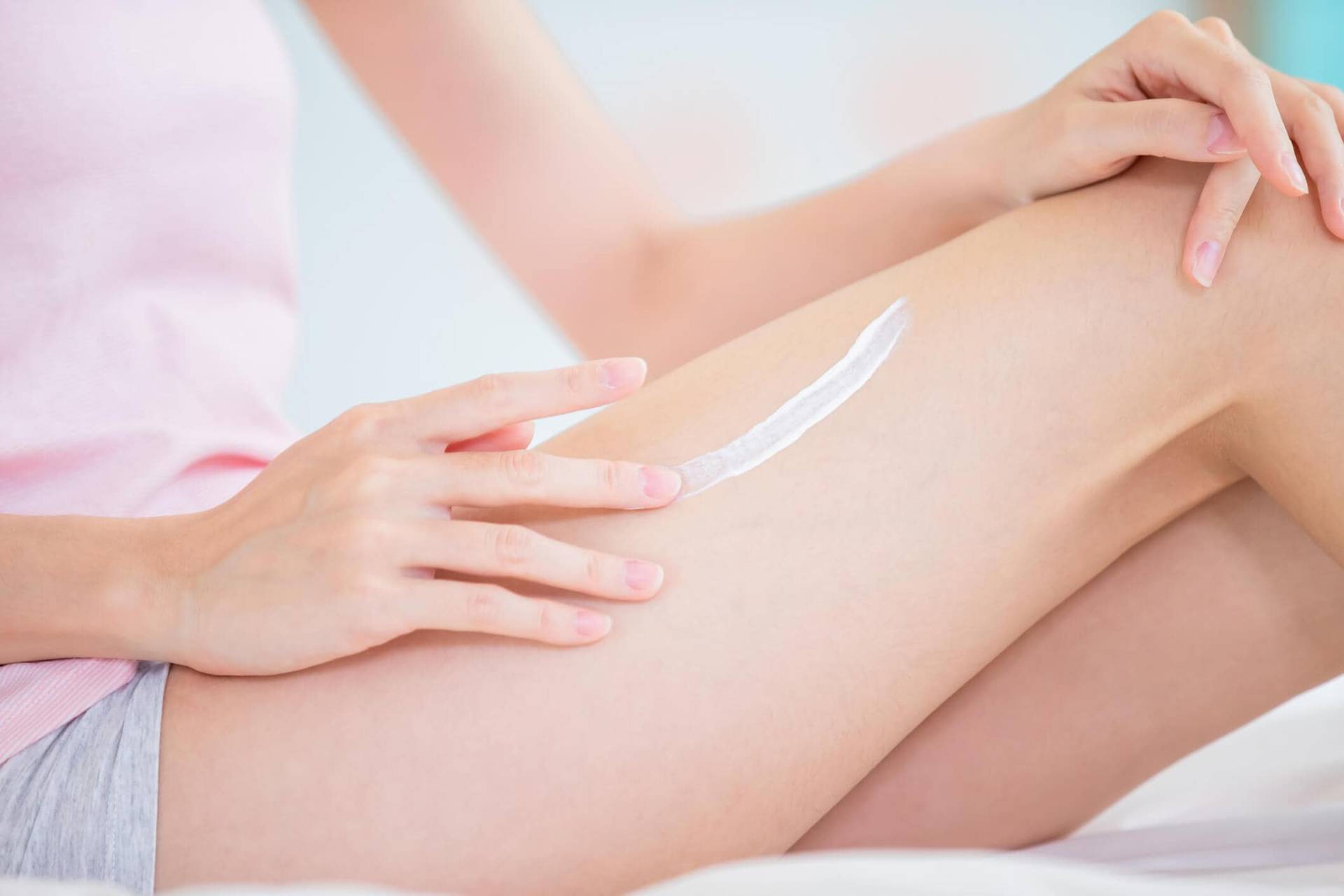 Personne appliquant de la crème sur sa jambe.
