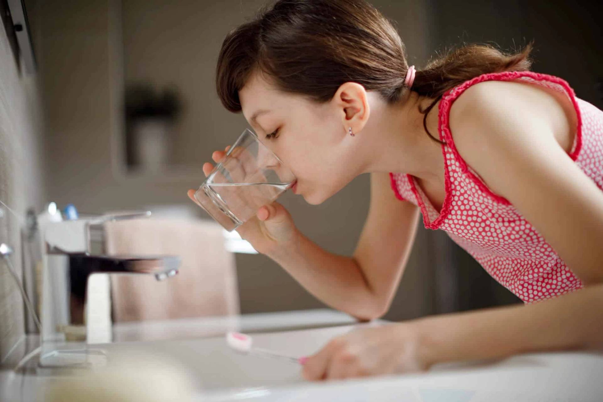 Personne se rinçant la bouche au-dessus d’un lavabo.