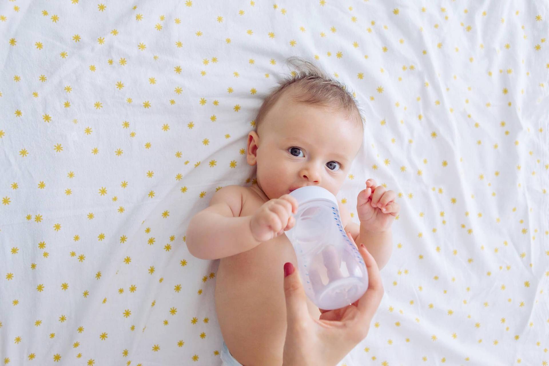 Bébé allongé buvant au biberon.