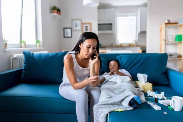 Adulte au téléphone près d’une personne allongée avec une couverture.