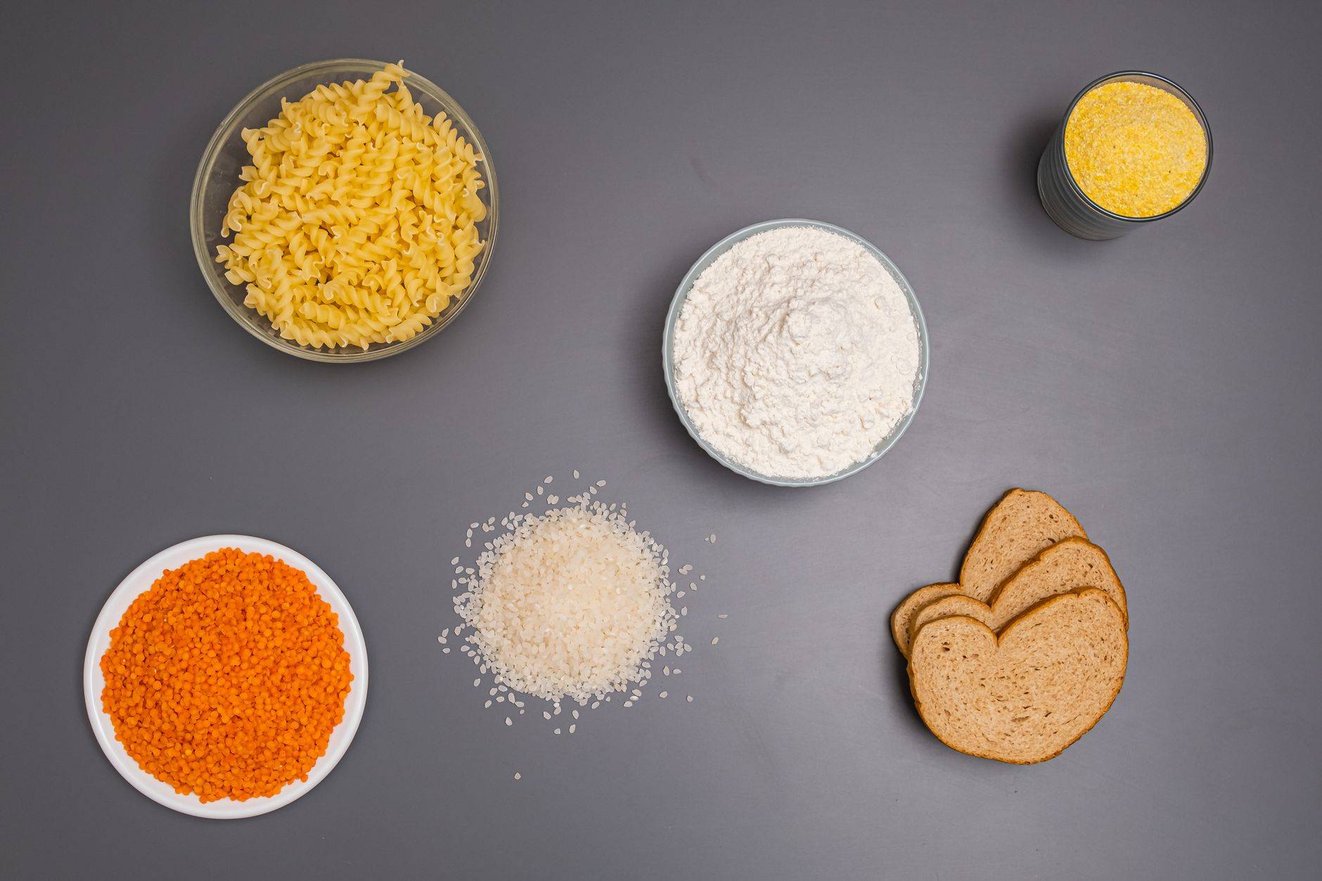 Pâtes, riz, farine, lentilles et autres ingrédients secs disposés dans des bols.