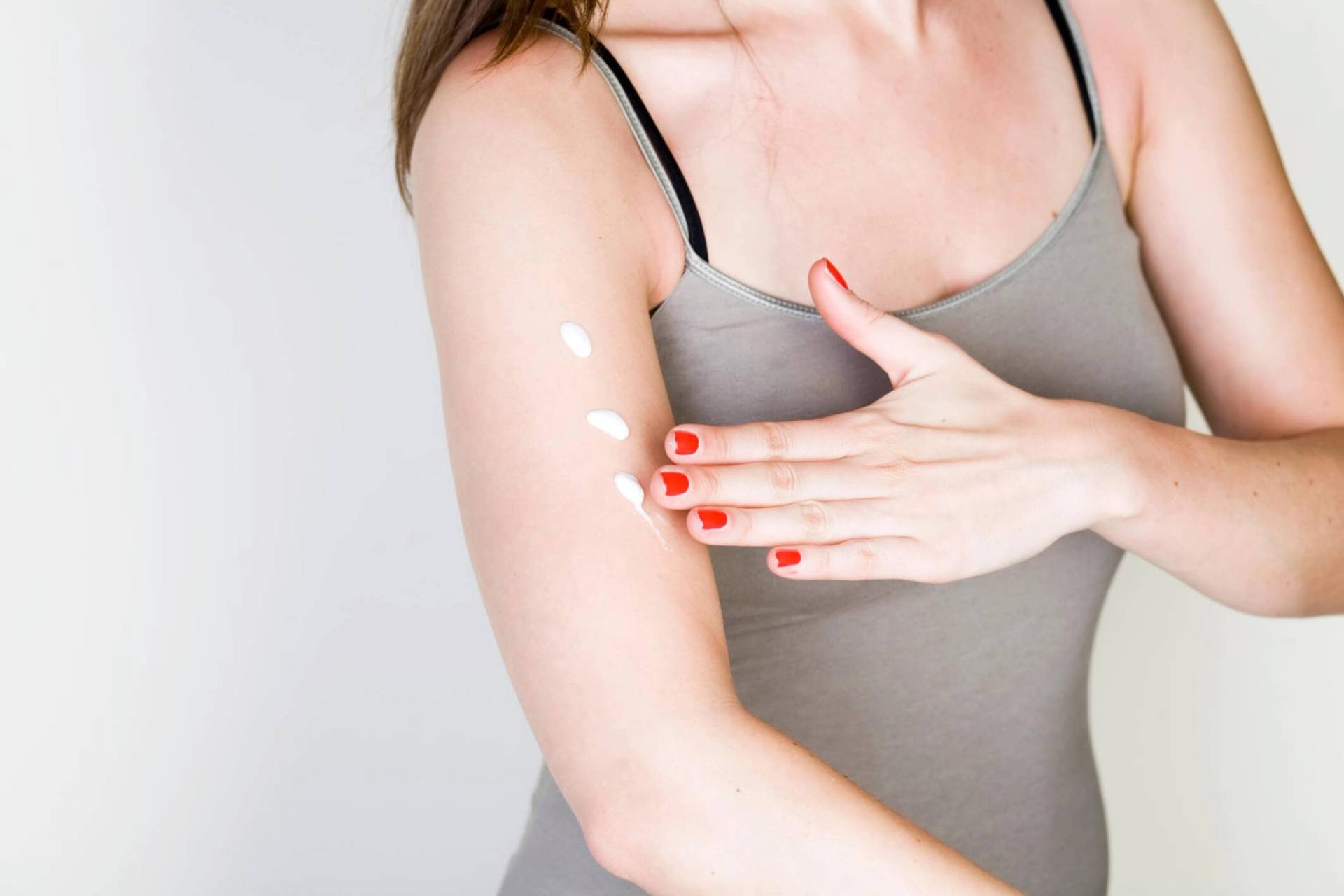 Personne appliquant de la crème sur son bras.